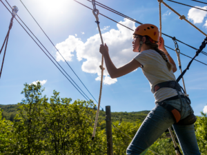 Girl scaling outdoor ropes course.