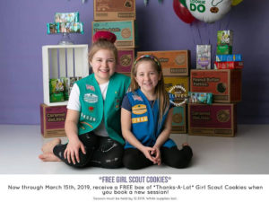 Two girl scouts sisters posed in front of their cookie packages.